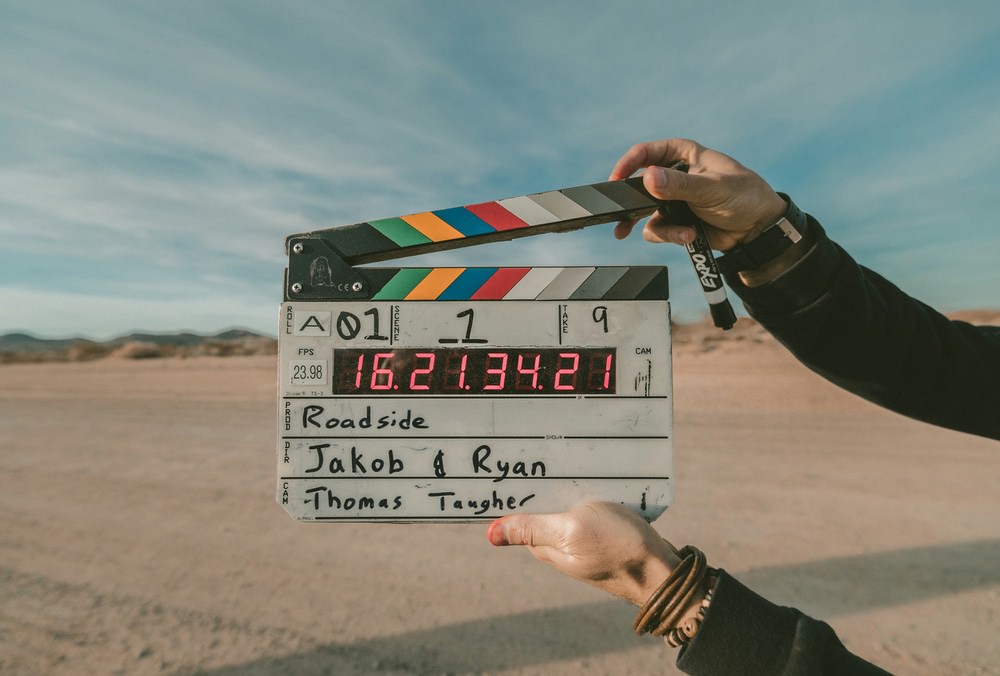 Hands holding a clapperboard showing timecode in a desert location